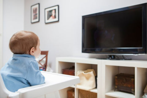 baby in high share looking at an off tv