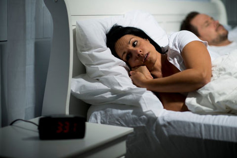 the impact of blue light on sleeping and melatonin. Couple in bed, woman wide awake