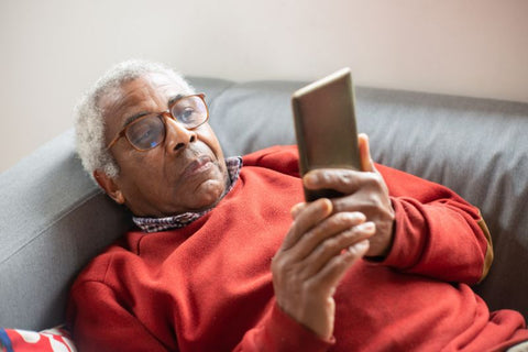 older man on sofa staring at phone