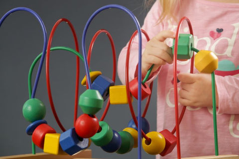child playing with toy that involves moving blocks along a chain