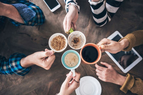 four people cheersing with cups of coffee