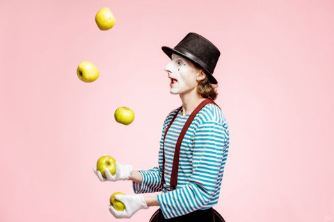 testing hand eye coordination via juggling. Juggler stands with apples in the air on a pink background