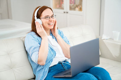 woman sat on sofa listening to music through headphones