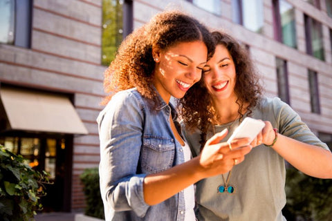 two women look at blue light cellphone outside