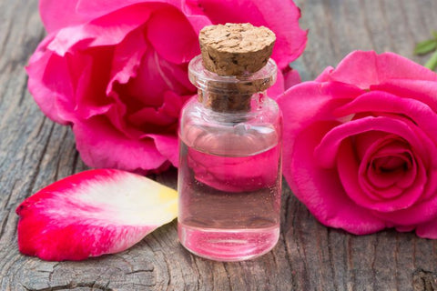 bottled rose water surrounded by rose petals