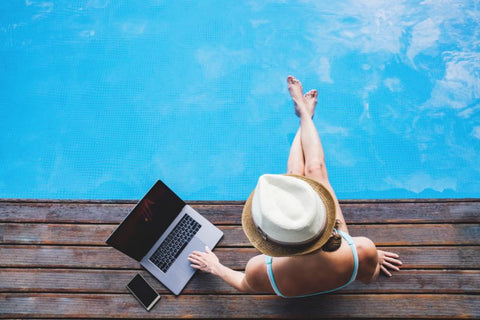 mujer junto a la piscina con laptop