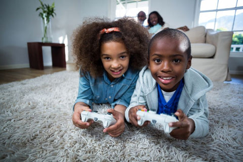 two kids leaning forward with controllers in hand playing games