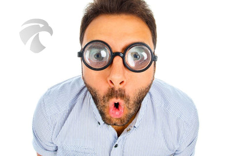 man staring shocked through distorted glasses that make his eyes look huge