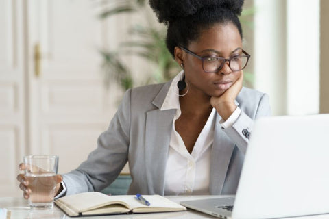 woman wearing glasses looking at her computer