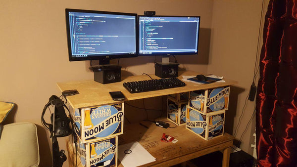 two screens mounted on a plank held together by blue moon beer packs