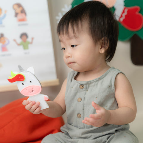 young baby holding finger puppet