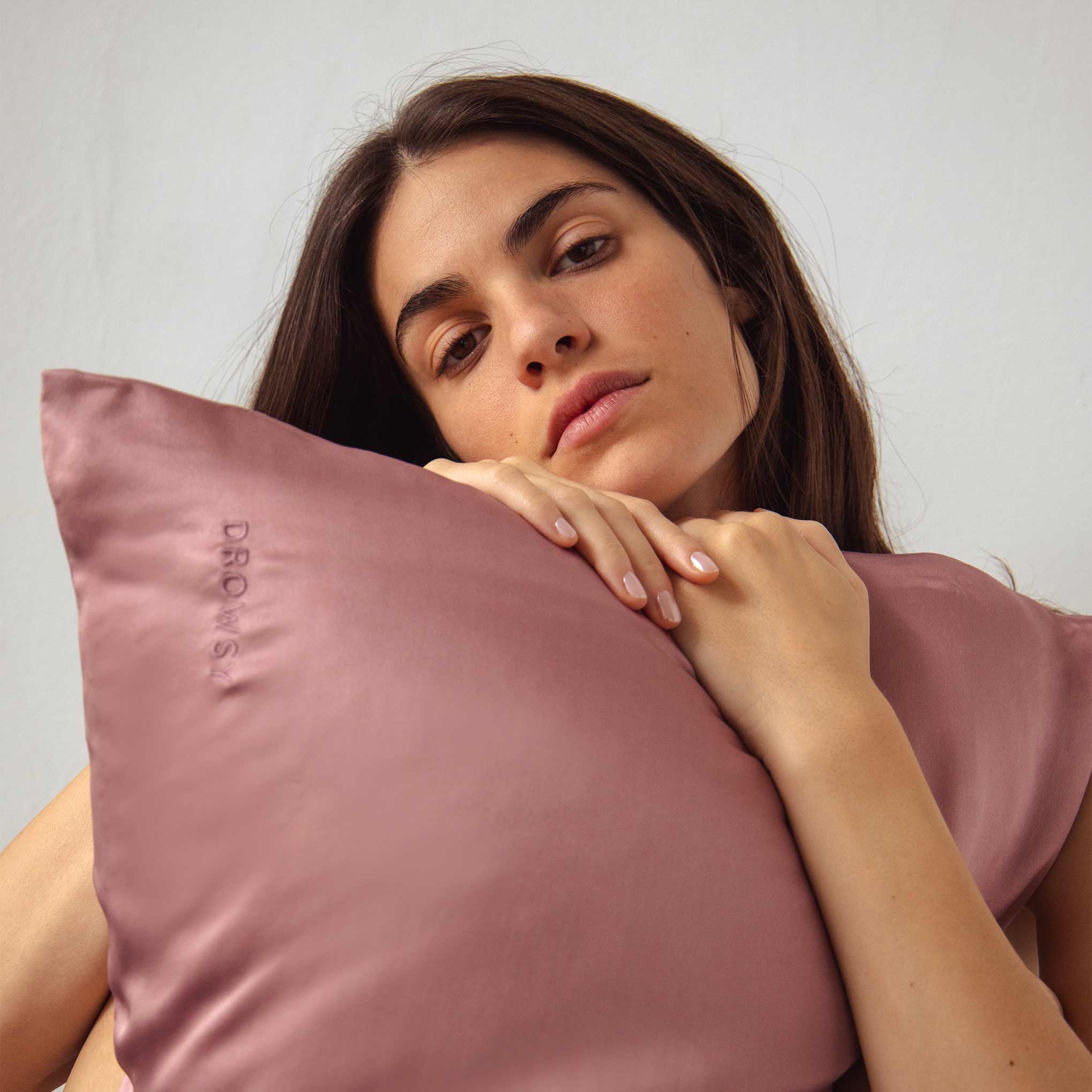 Female model hugging pink coloured Drowsy Silk Pillowcase