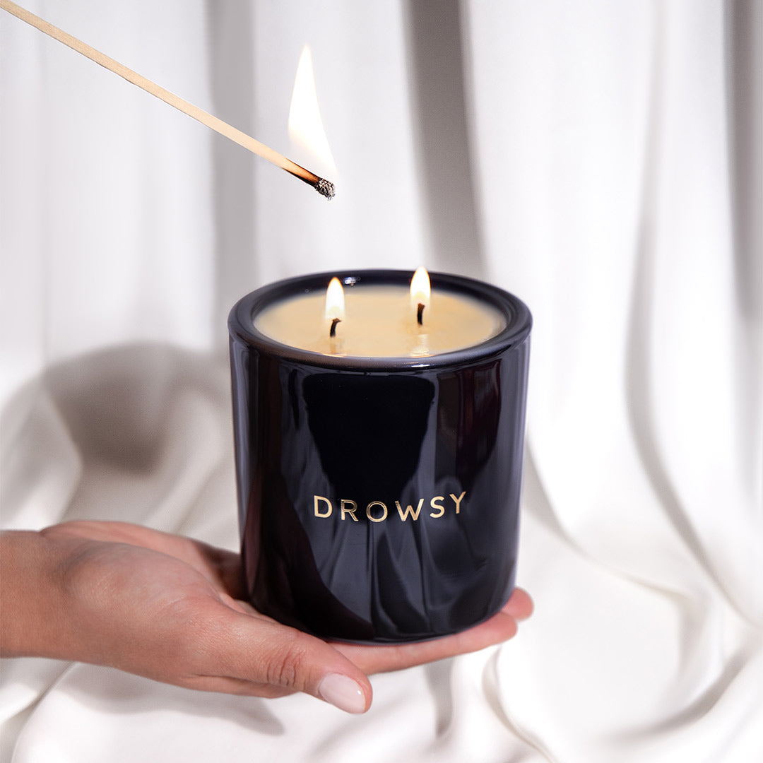 Hand lighting the Drowsy Sleep Co. Sleep candle with a long match