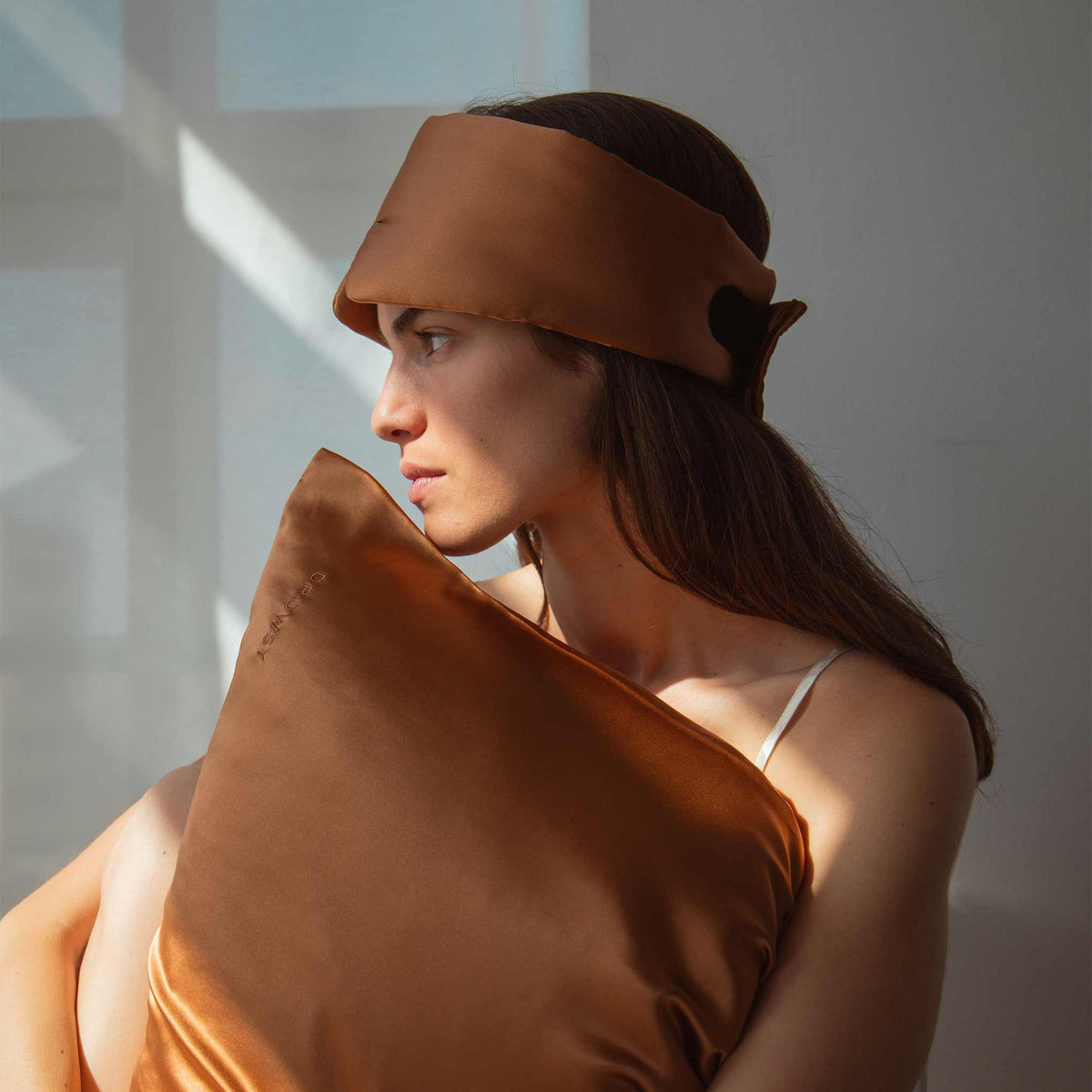 Female model holding terracotta coloured Drowsy Silk Pillowcase