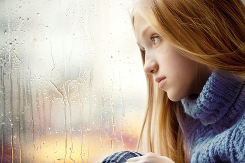 Woman looking out rainy window
