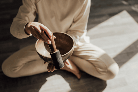 A Person Using a Tibetan Singing Bowl while Sitting on the Floor