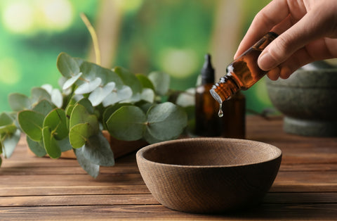 pouring eucalyptus essential oil into a wooden bowl