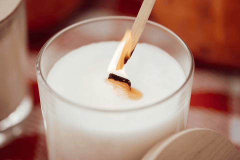 Igniting white aromatic candle with wooden wick
