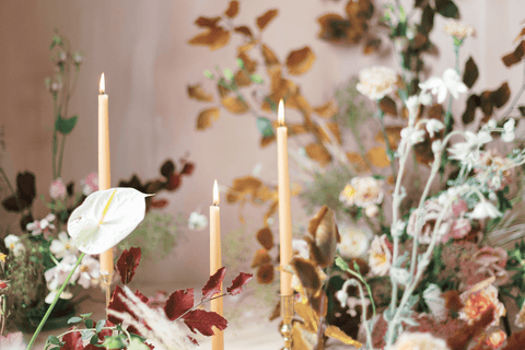 lit tapered candles in natural floral arrangement