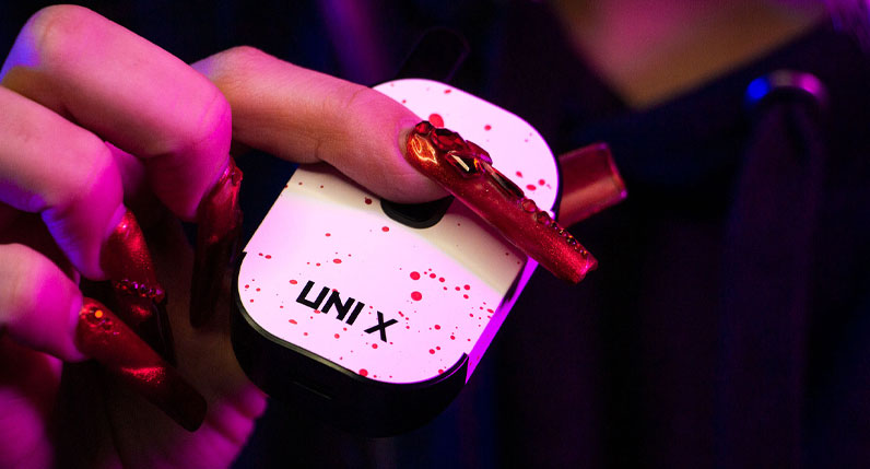 Wulf UNI X en manos de mujer con iluminación azul rosa suave