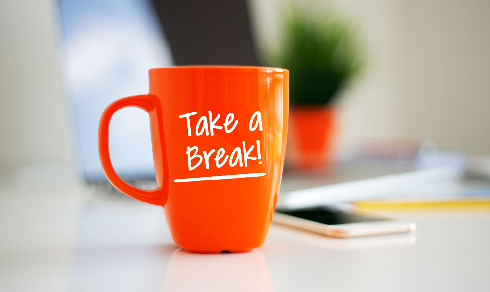 Mug that says "take a break" sitting on a desk