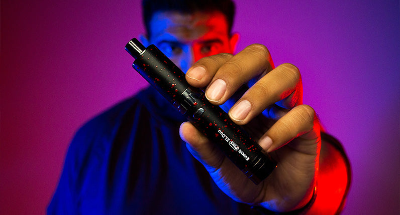 man holding Wulf Evolve Duo 2 in 1 Dry herb mode inside studio with purple lighting