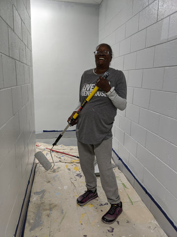 black woman holding paint roller laughing