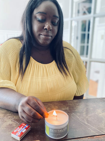 black woman lighting a candle in a white tin with a match