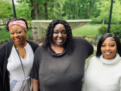 three black women smiling and looking at the camera