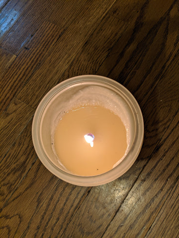 An example of candle wax pooling evenly within its glass container