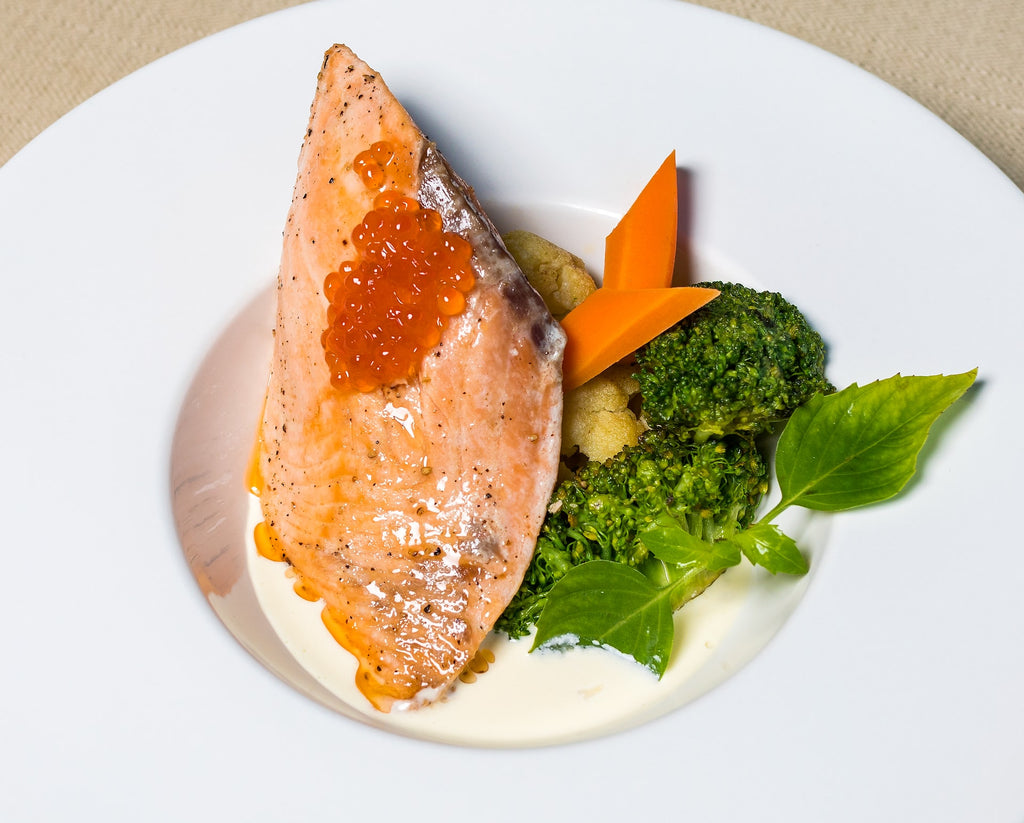 Salmon with salmon roe pictured on a plate with broccoli.