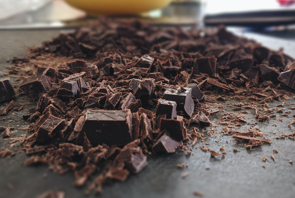 Dark chocolate chopped and spread on a large counter.