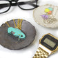 dino-snore t-rex dinosaur necklace in a trinket dish