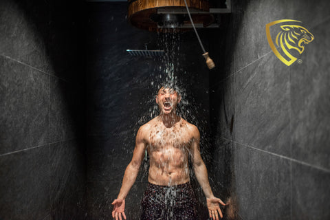 Man verfrist zich met een koude douche, terwijl hij zich voorbereidt op zijn fitnessroutine en gebruik maakt van producten van Apexnutrition om zijn lichaam in topvorm te houden