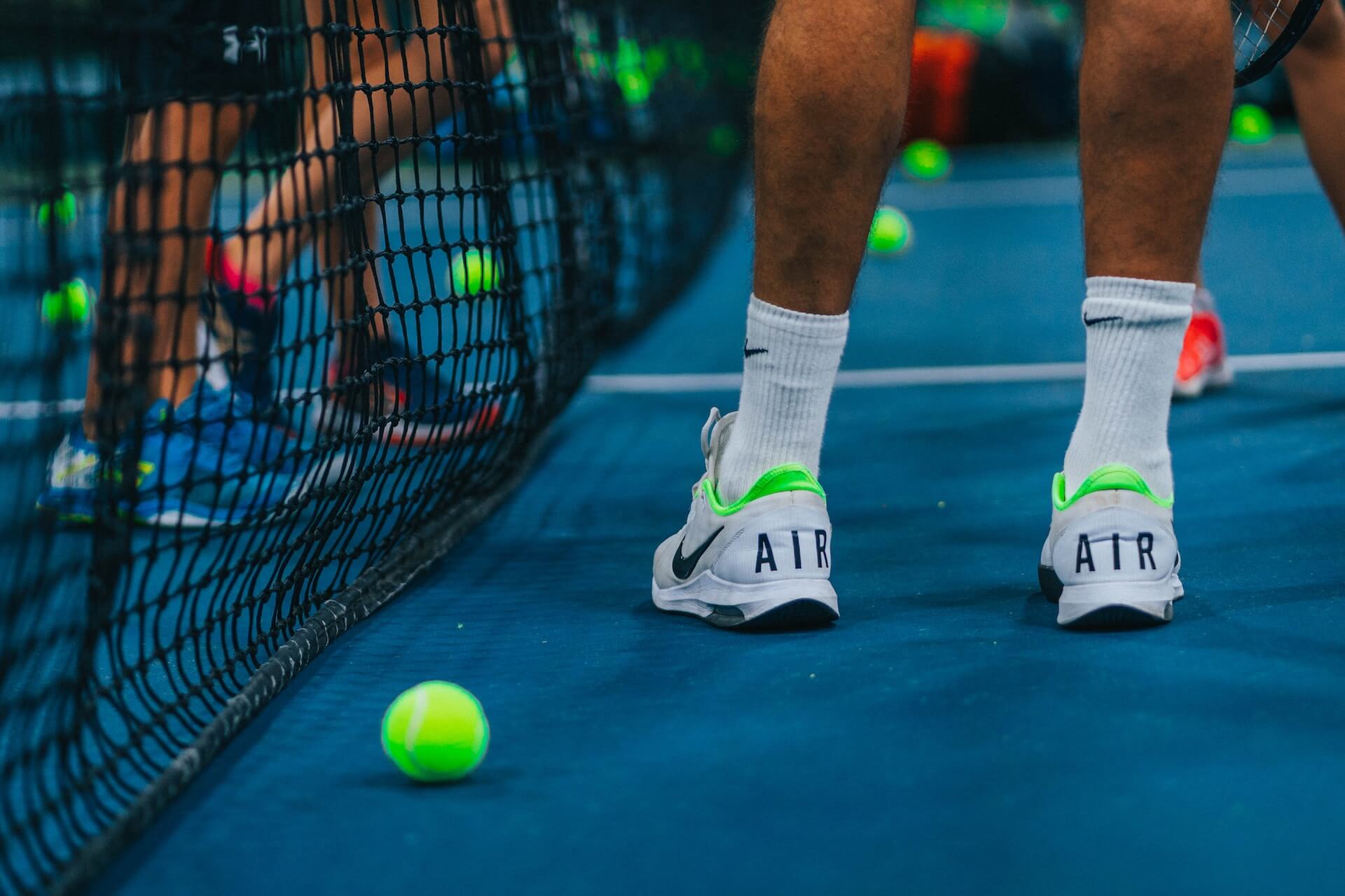 person in tennis shoes and socks standing on tennis court