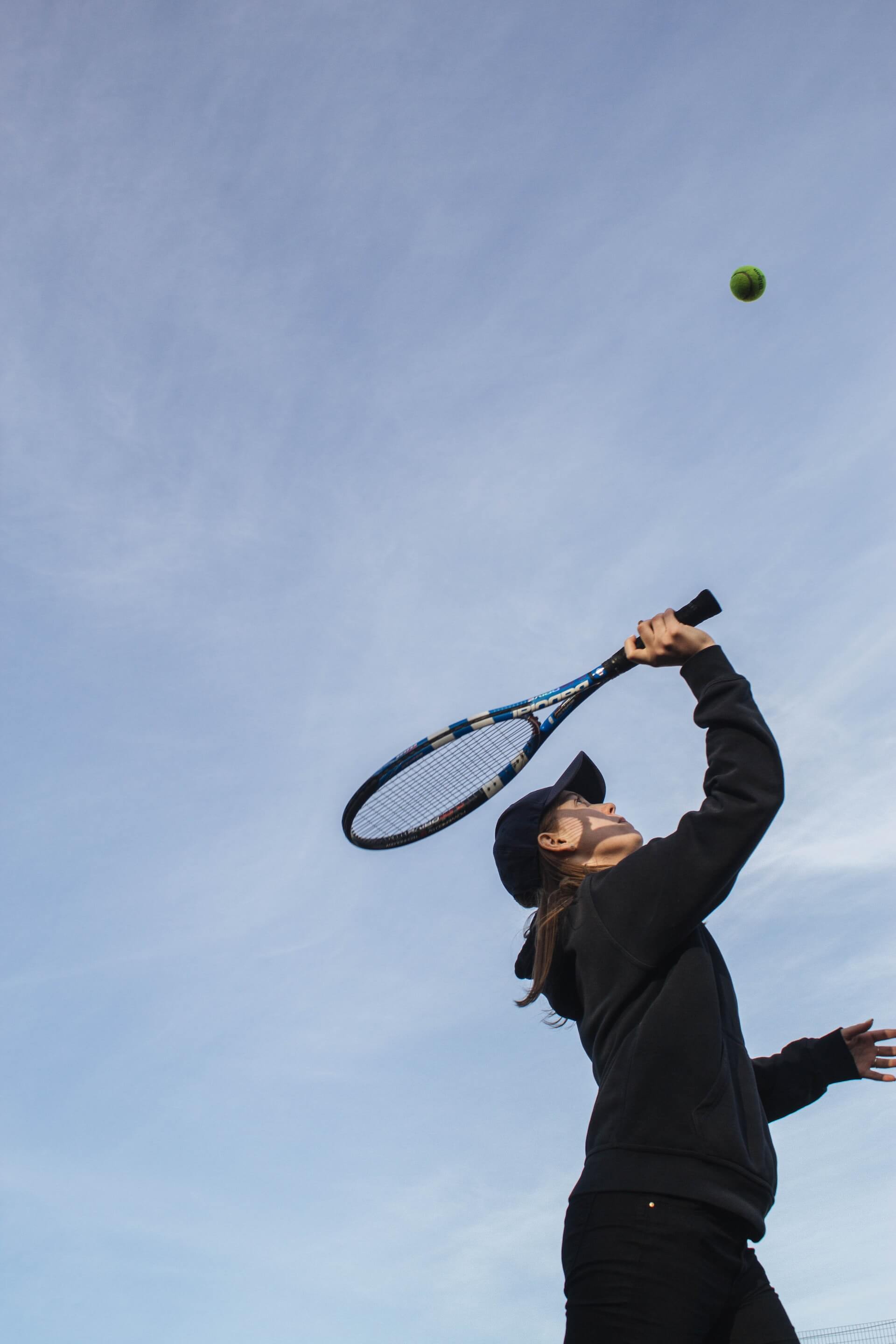 person in winter tennis clothes swinging racquet