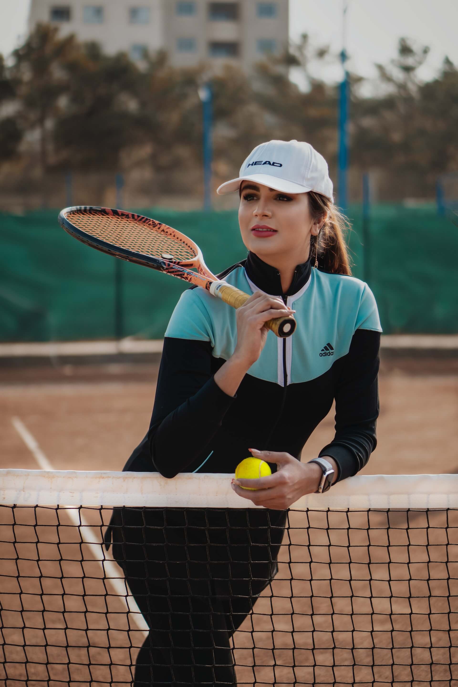 woman holding tennis ball and racquet on a tennis court
