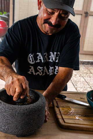 Arnie Segovia grinding spices in a molcajete
