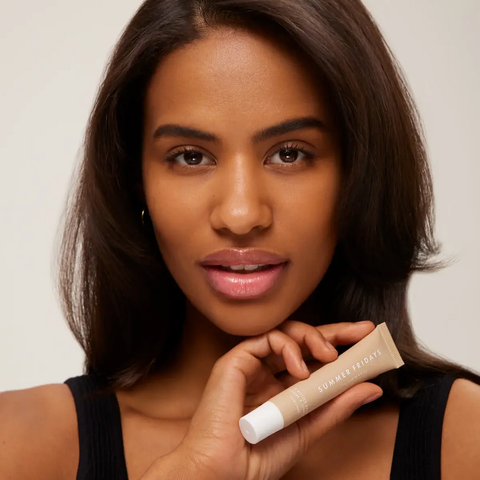 A model wearing and holding the Lip Butter Balm in Vanilla Beige from Summer Fridays.