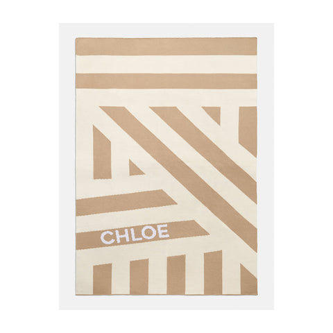 The Criss Cross Custom Blanket in Neutral/Beige from ​​BaubleBar with the name "Chloe" on it.