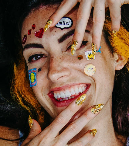 Braelinn Frank smiling with stickers on her face and colorful nails.