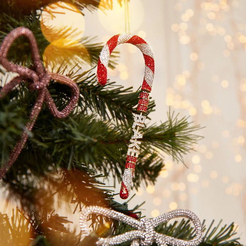 Mint to Be Custom Ornament (a sparkly candy cane with a name) from ​​BaubleBar hanging on a Christmas tree.