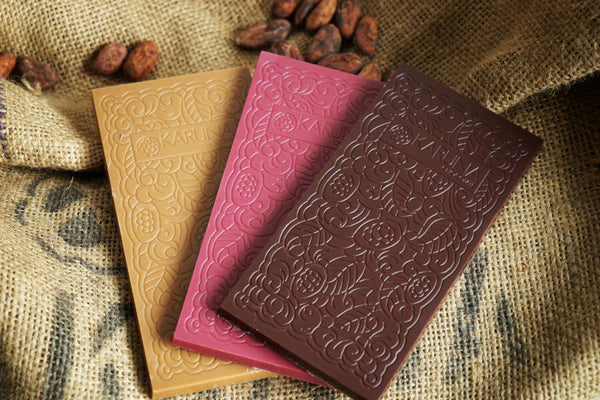 Drei ausgepackte Schokoladentafeln von Karuna Chocolate auf Kakaosack