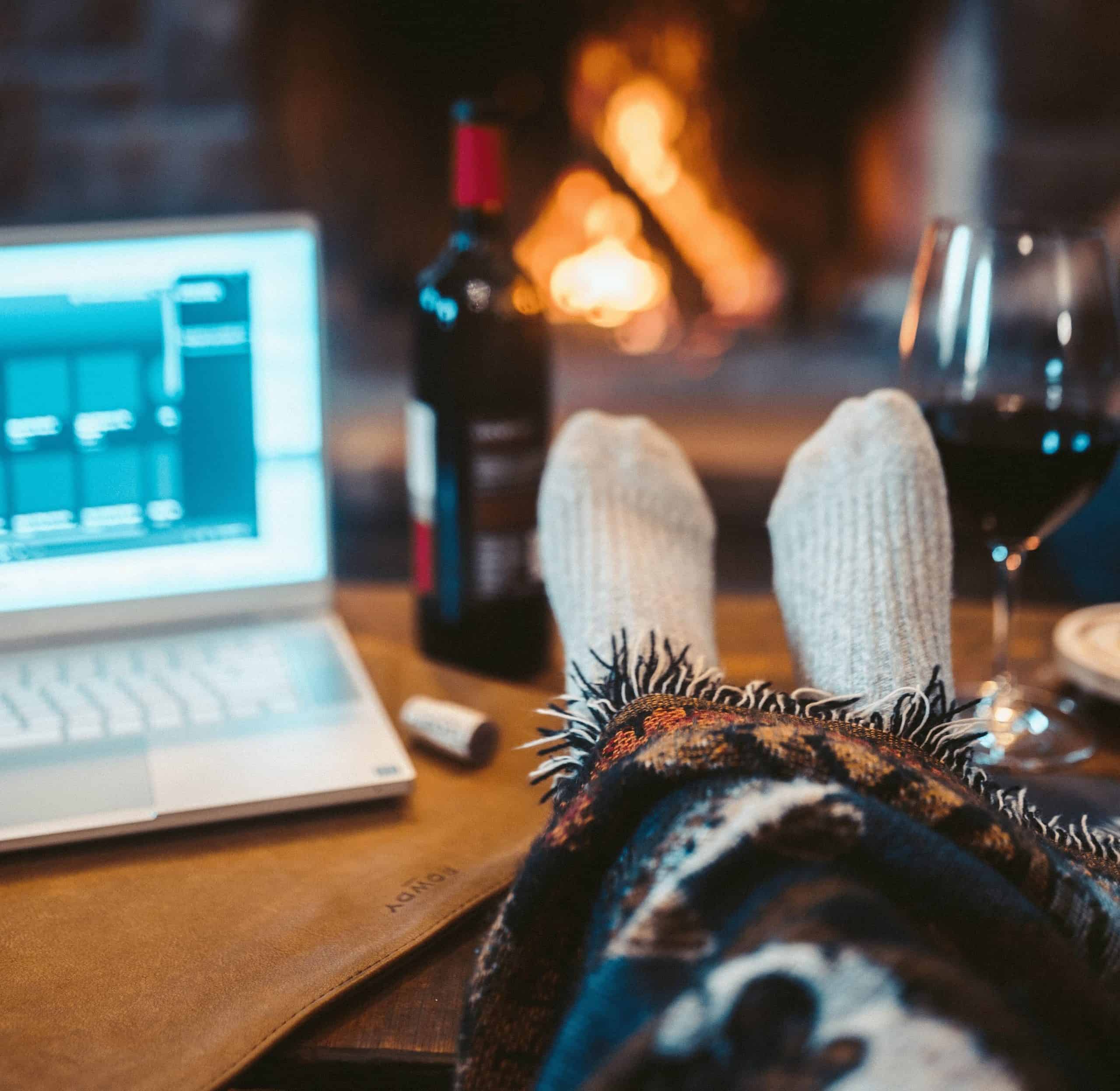 feet up on table with laptop and wine