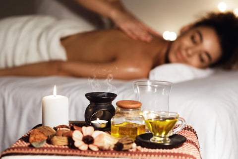 African woman enjoying aromatherapy massage in luxury spa with candles on foreground