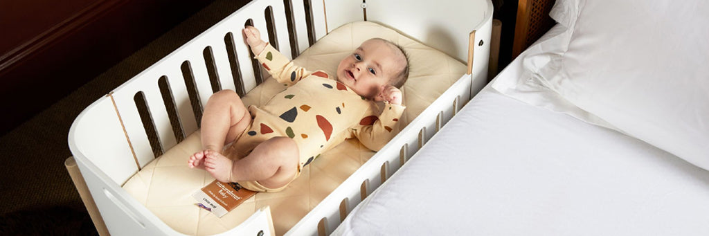 A baby in a co-sleeping crib.