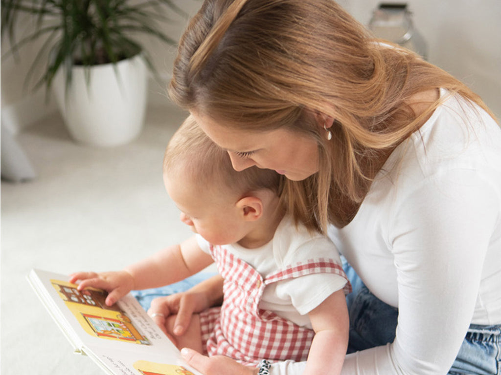 Lucy, founder of NEST, reading a story to a baby.