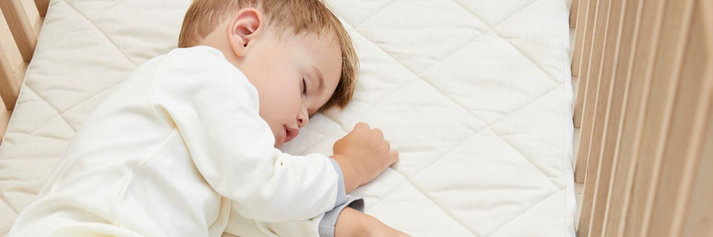 A baby sleeping on a Naturalmat Baby mattress.