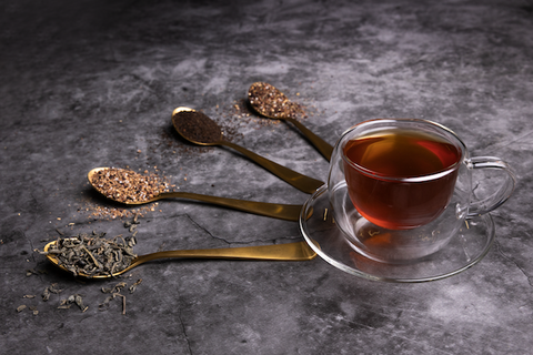 Black tea cup with spoons of different loose leaf tea