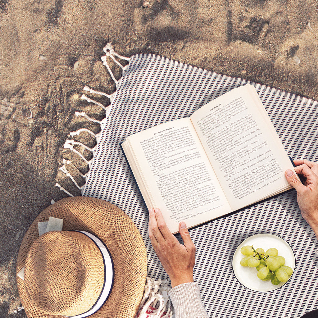 woman reading on a beach with towel